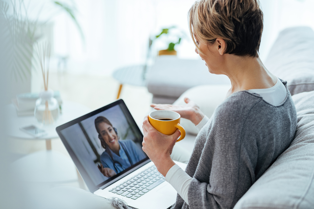 Woman sitting on the sofa while making video call over laptop with her doctor at THe Cusp