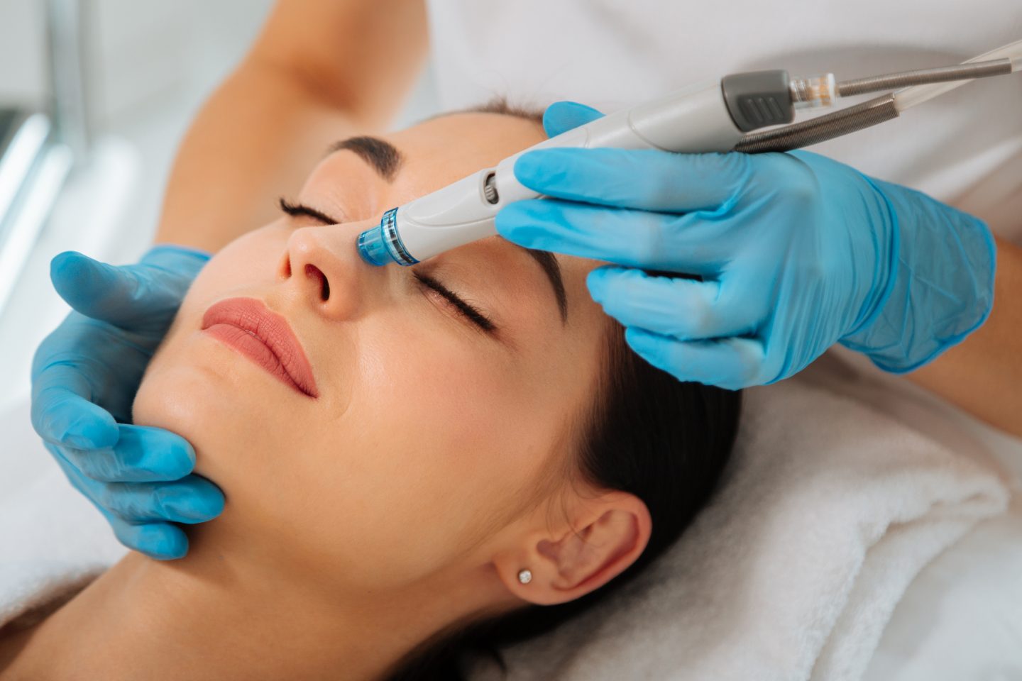 Facial procedure. Delighted nice woman lying on the medical bed with her eyes closed while having a diamond glow facialhydrafacial