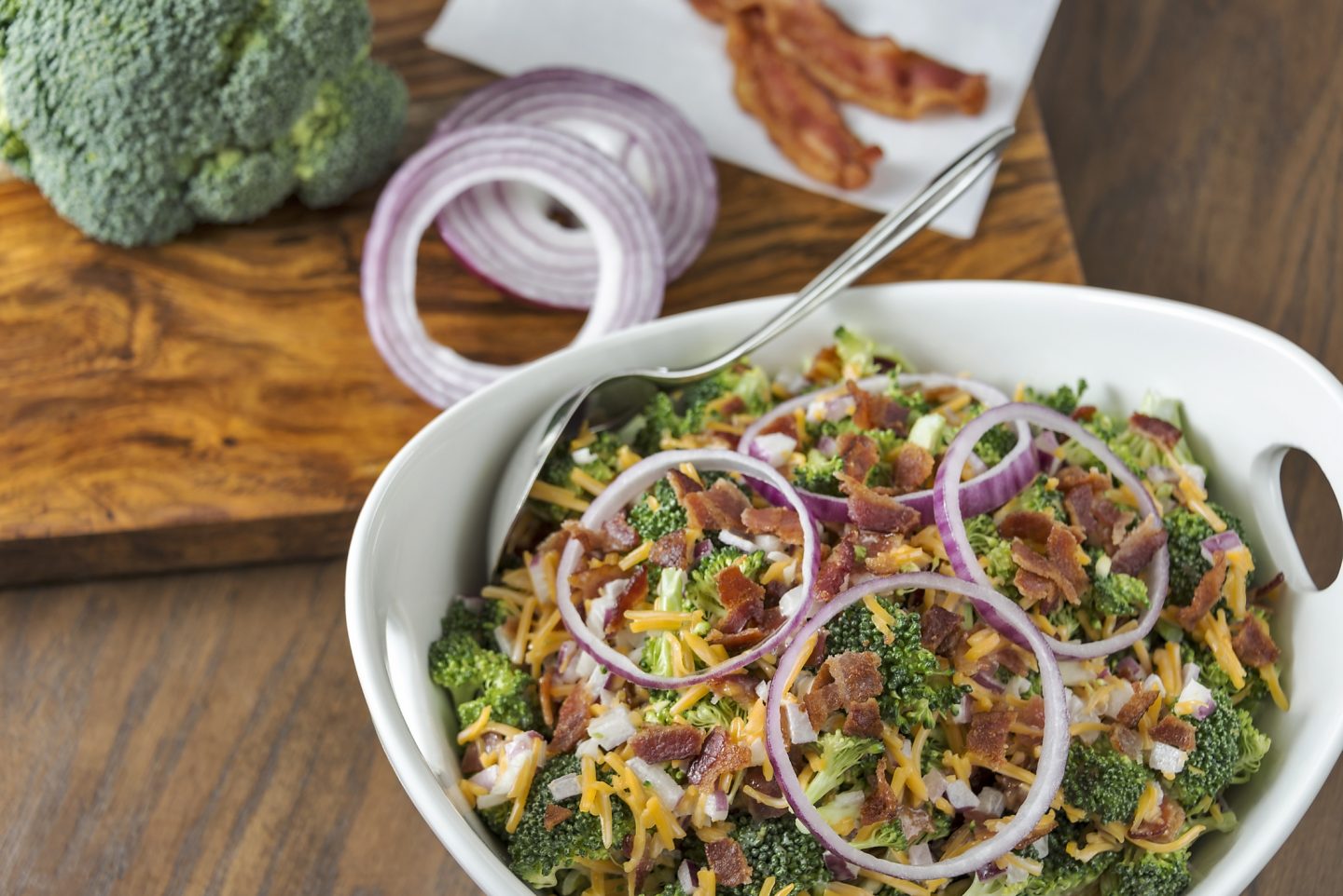A bowl refreshing broccoli salad with ingredients. Selective focus was used on the image and copy space was left in 2 corners.