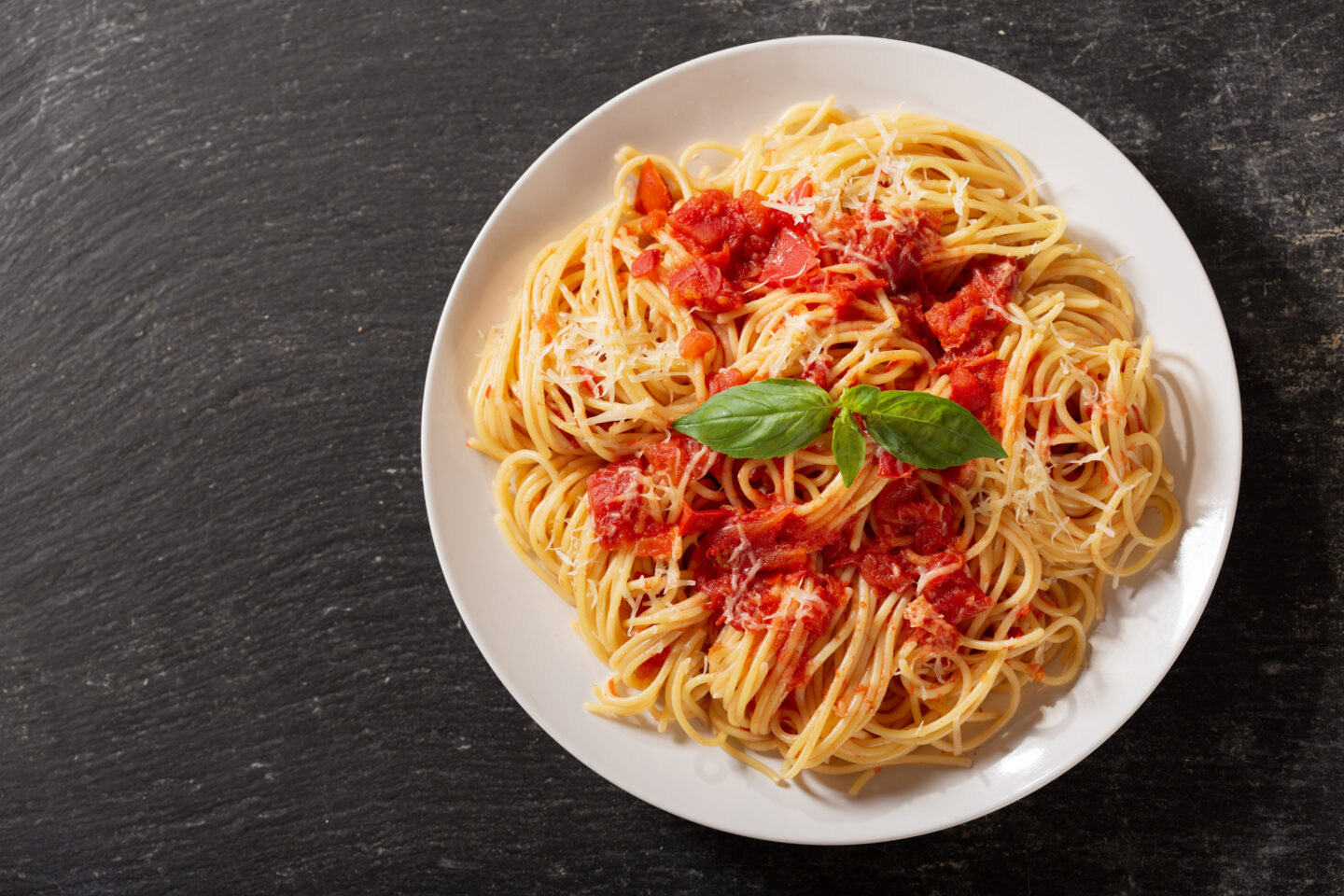 plate of pasta with tomato sauce on dark table, top view