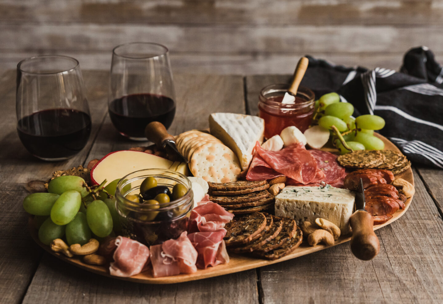 Close up of charcuterie board and glasses of wine on wooden table. 