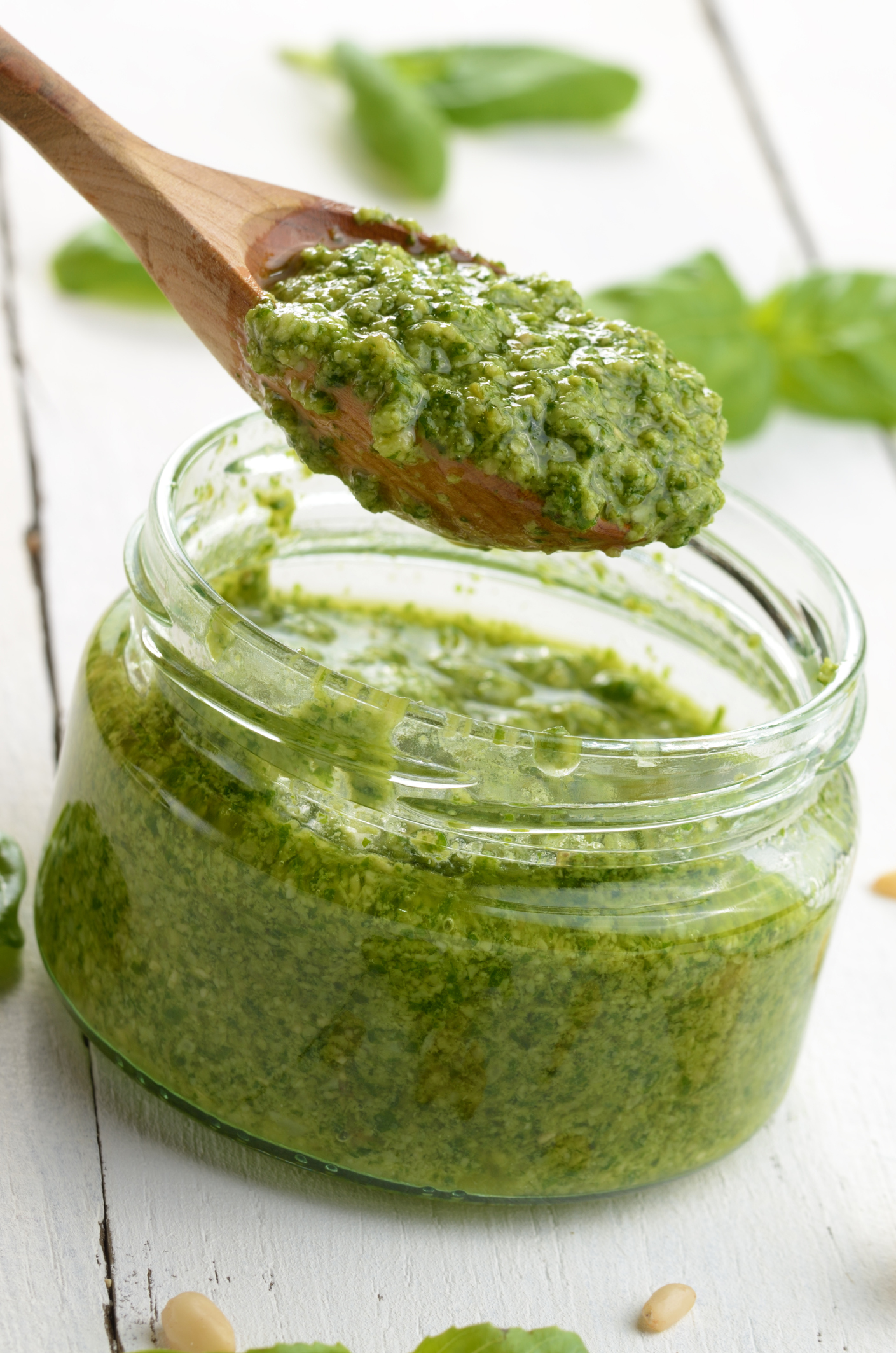 Glass jar of pesto sauce with wooden spoon