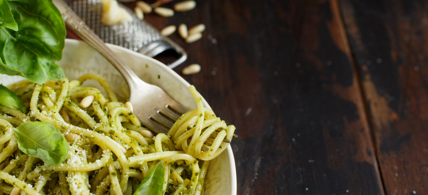 Spaghetti pasta with pesto sauce, basil, pine nuts and parmesan close up