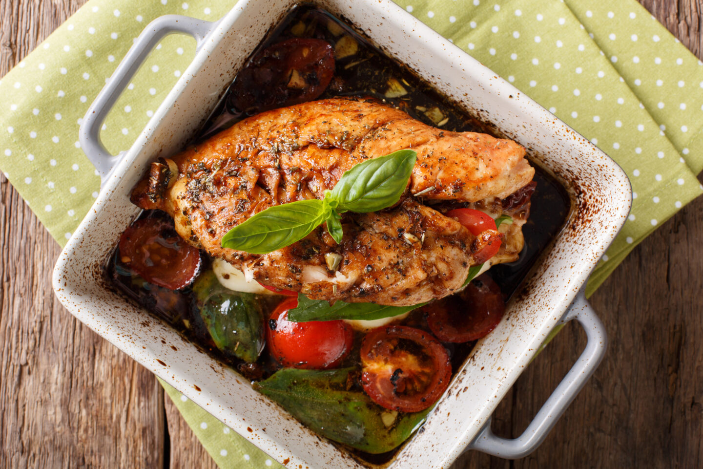 Delicious chicken fillet baked with caprese close-up in a baking dish on a table. horizontal view from above