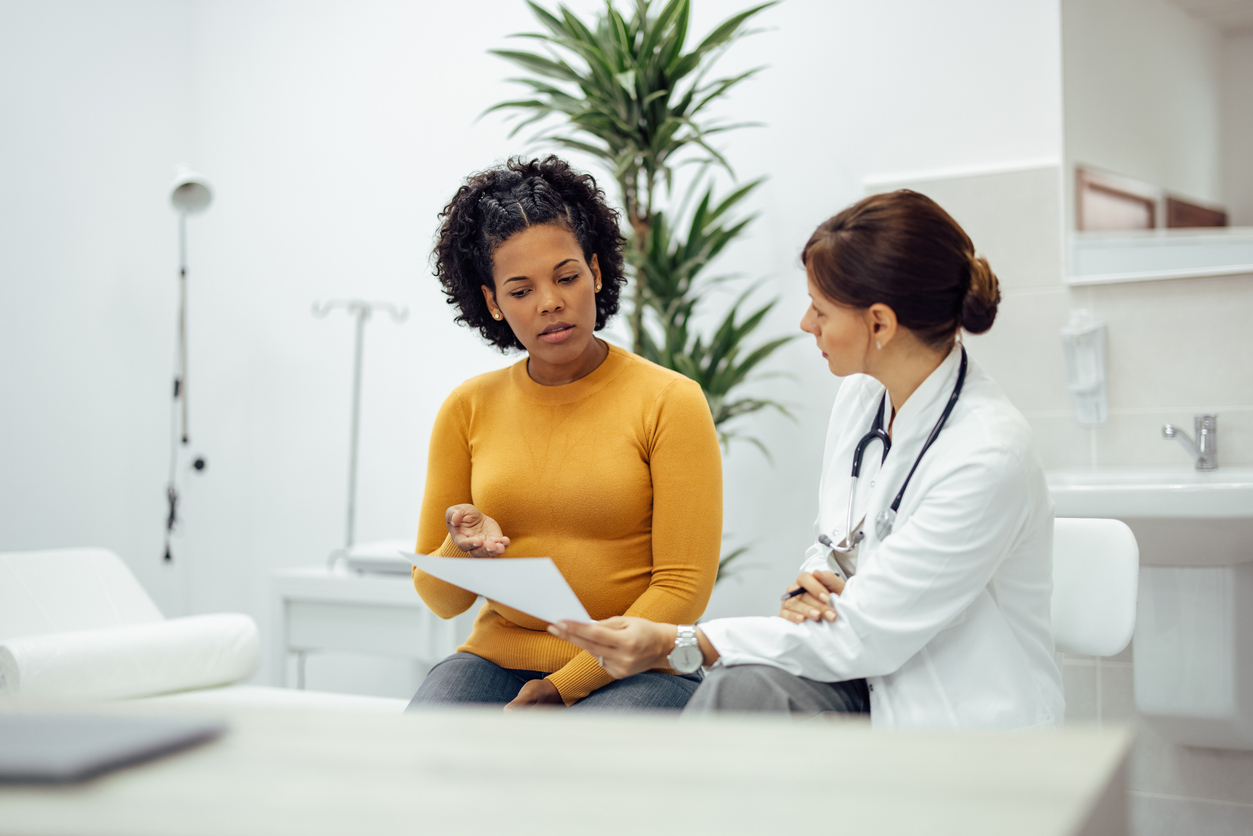 Female patient and doctor discussing test results in a medical office.