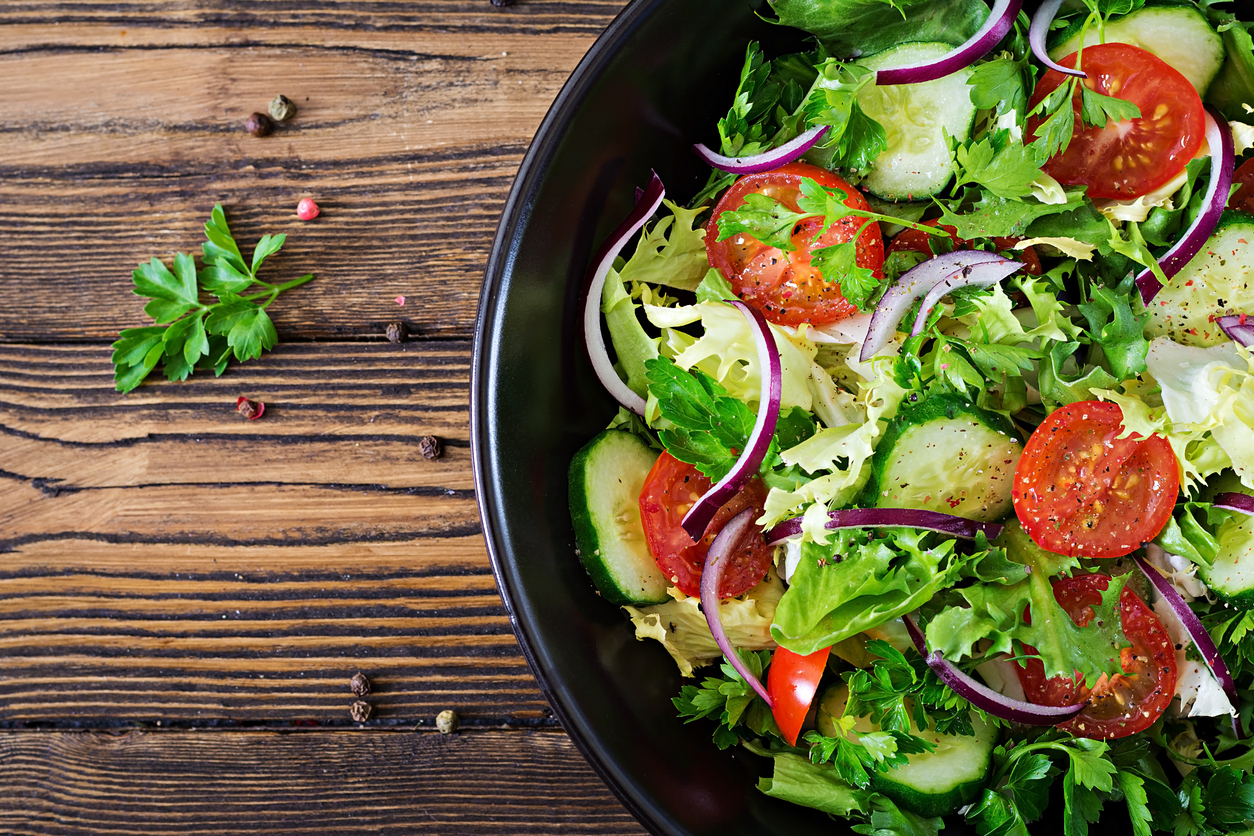 Salad from tomatoes, cucumber, red onions and lettuce leaves. Healthy summer vitamin menu. Vegan vegetable food. Vegetarian dinner table. Top view. Flat lay