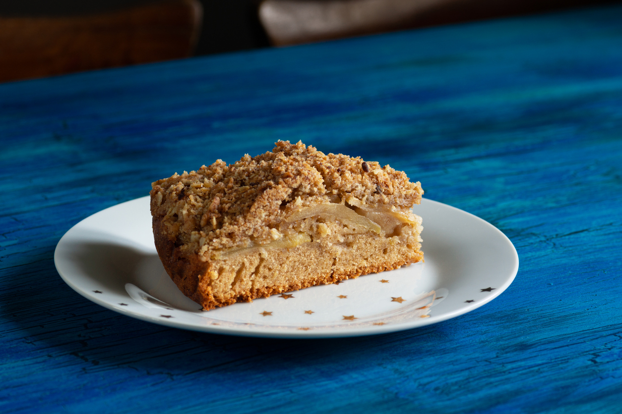 A single slice of Irish apple cinnamon coffee cake with a streusel topping on a white plate with golden stars.