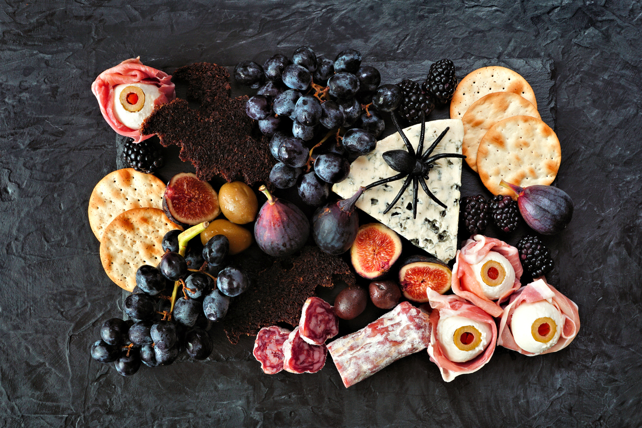 Halloween theme charcuterie board. Above view against a dark background. Assortment of cheese and meat appetizers.