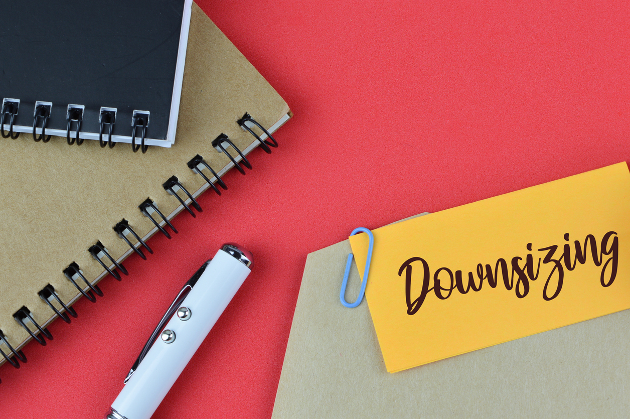 Top view of pen, notebook and memo note written with DOWNSIZING