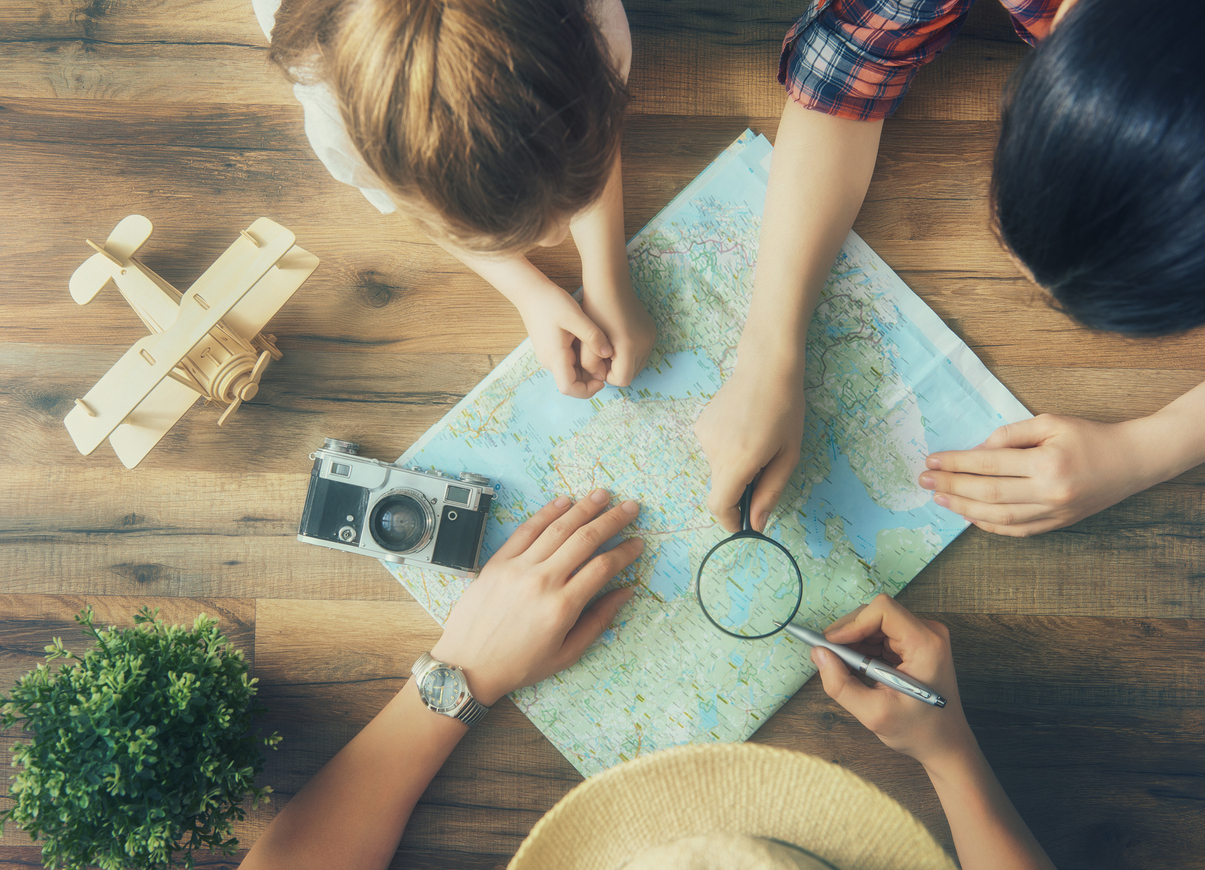Go on an adventure! Happy family preparing for the journey. Mom, dad and daughter study the map and choose a route of travel.