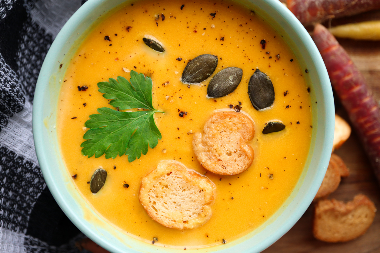 Bright yellow pumpkin soup with pumpkin seeds, croutons